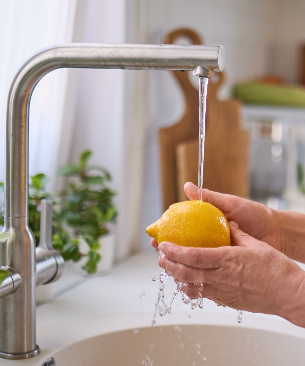 Person wäscht eine Zitrone unter fließendem Wasserhahn.