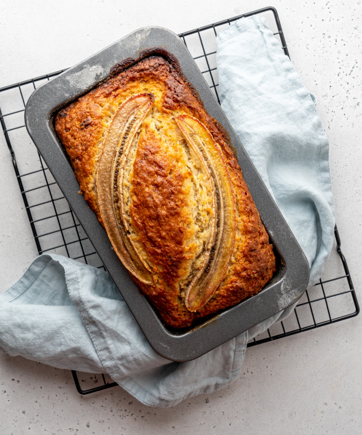 Frisch gebackenes Bananenbrot in einer Backform auf einem Kühlgitter.