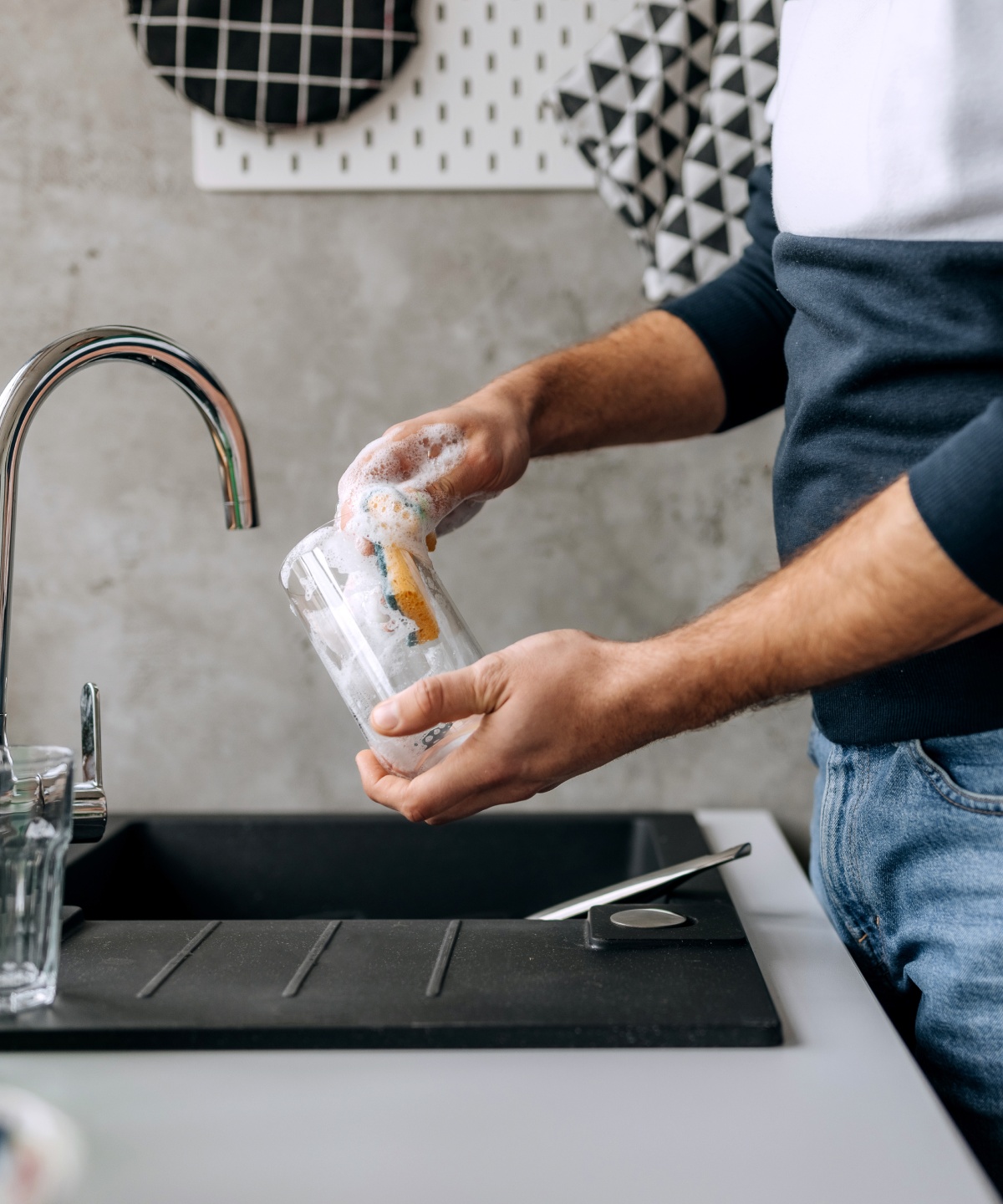 Mann spült ein Glas von Hand, um es für das Einkochen im Backofen vorzubereiten.
