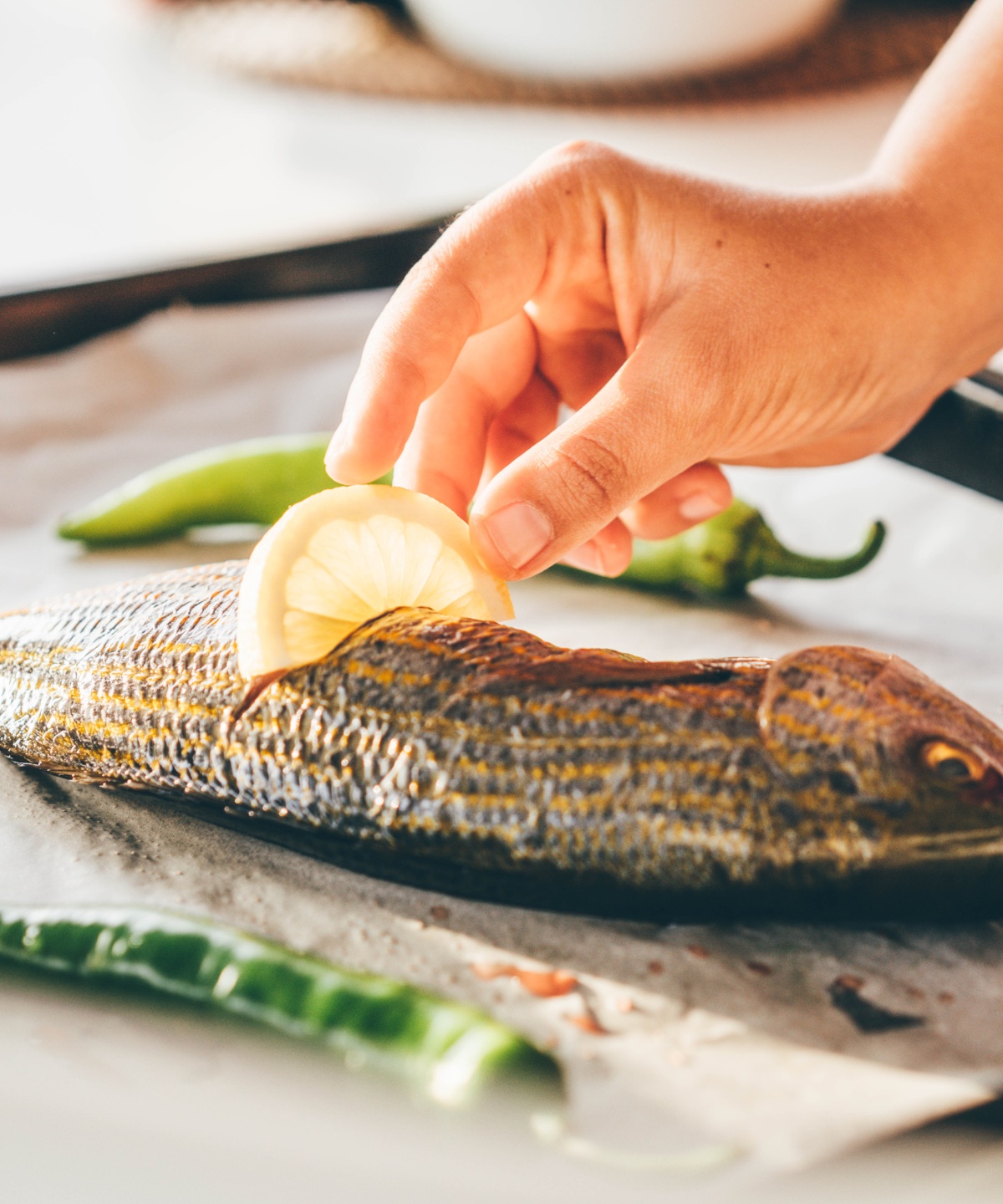Eine Person steckt eine Zitronenscheibe in eine gebackene Forelle.