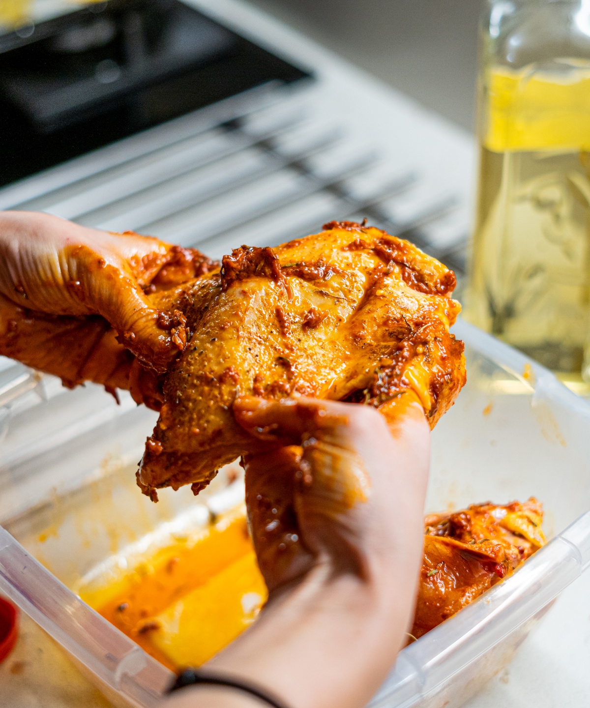 Eine Person mariniert eine Hühnerbrust mit den Händen.