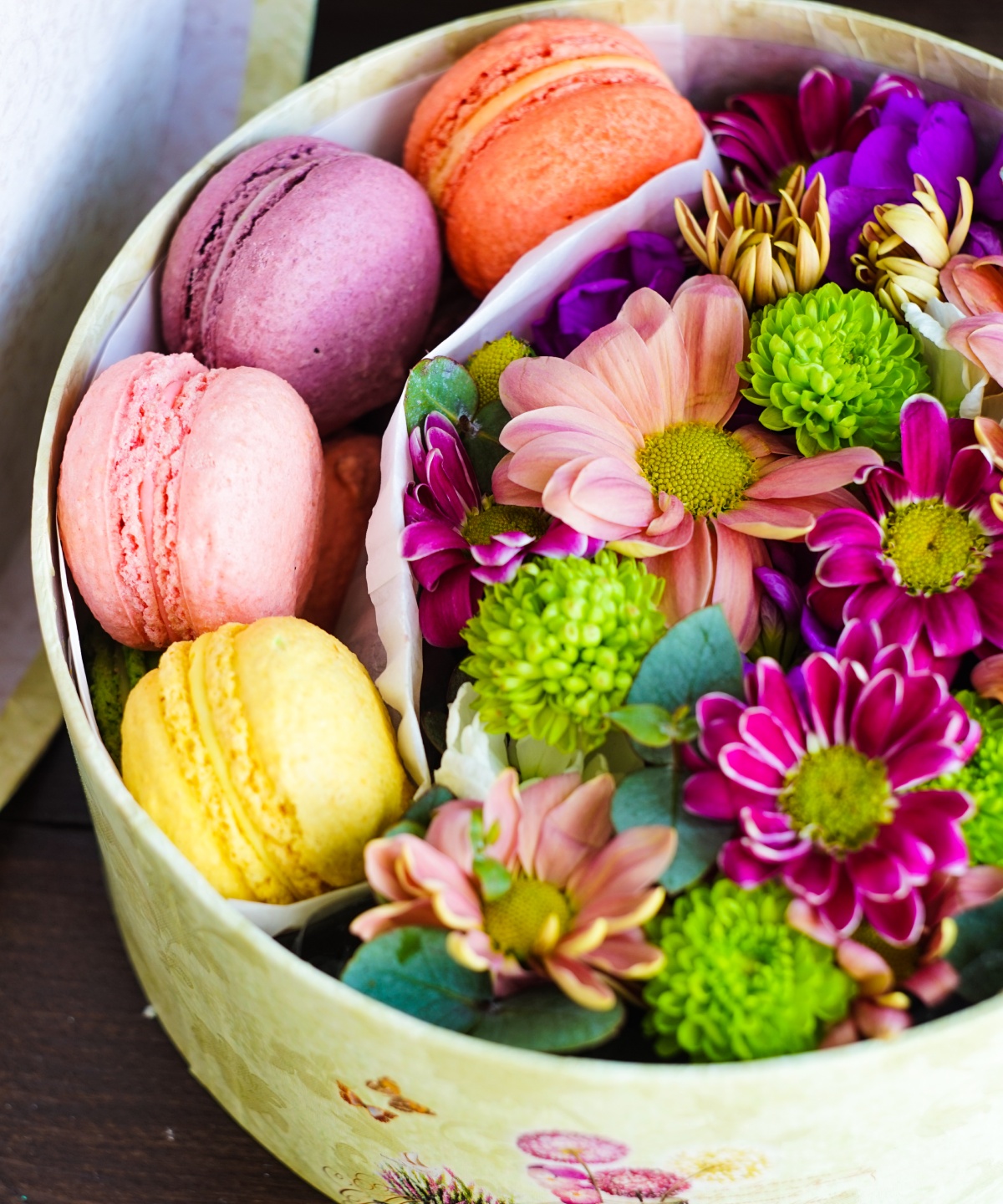 Eine Geschenkbox, gefüllt mit Blumen und bunten Macarons.