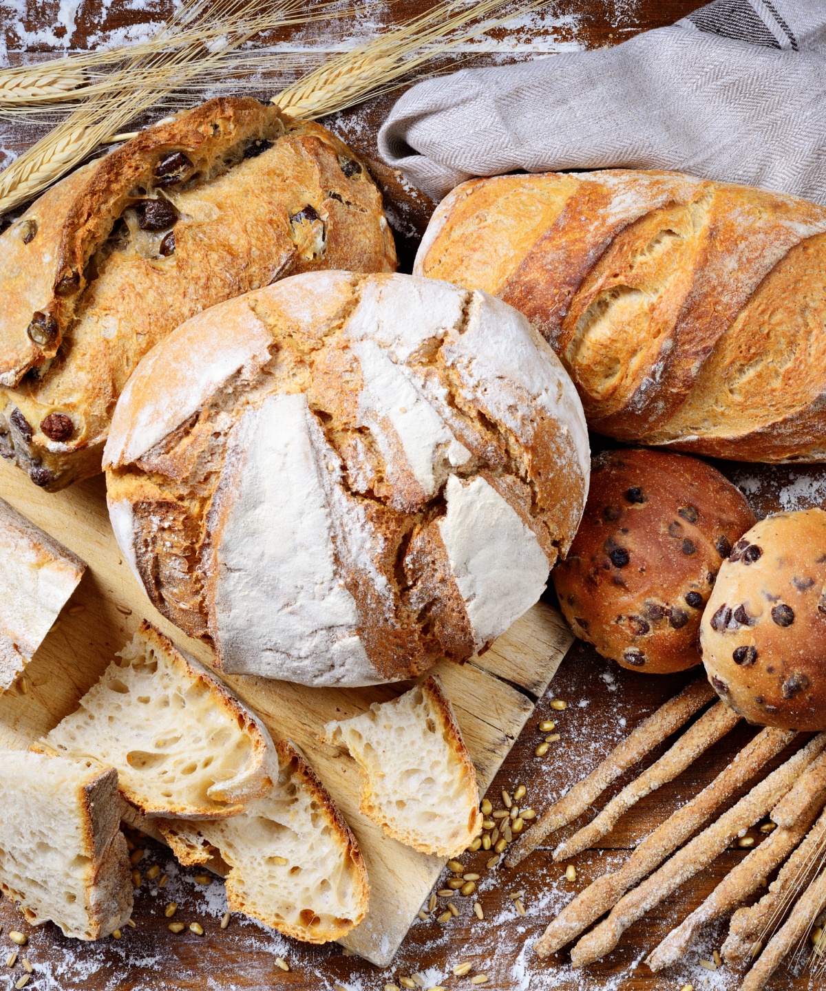 Knusprig gebackene glutenfreie Brote und Brötchen auf einem Holzbrett.