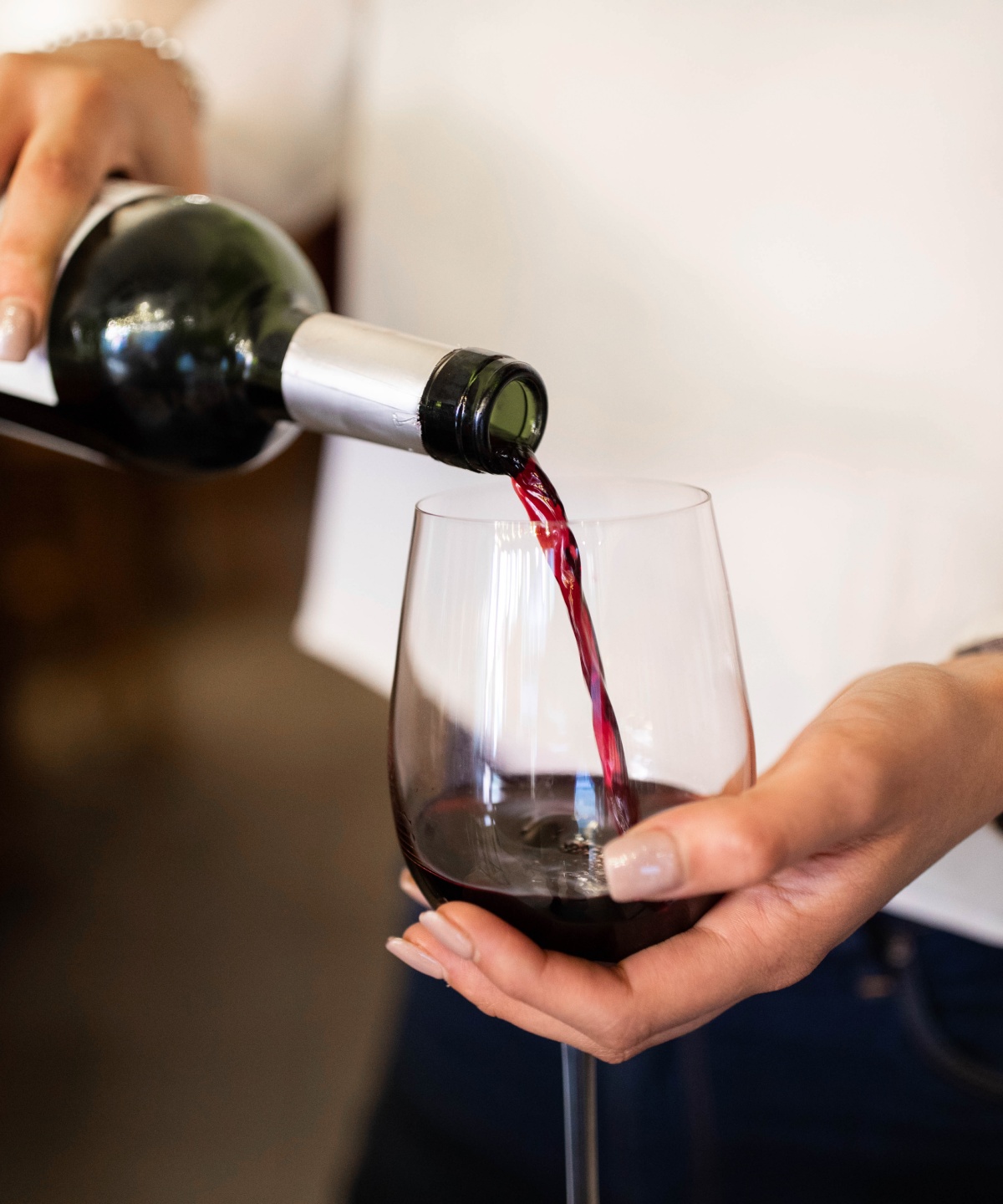Eine Person schenkt ein Glas Rotwein ein.