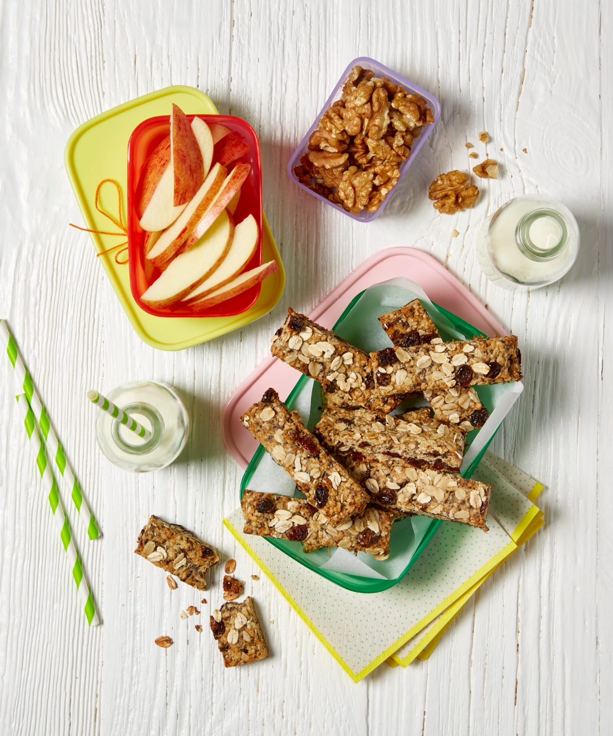 Leckere Zutaten für das Pausenbrot, wie Apfel, Müsliriegel und Nüsse liegen auf dem Tisch.