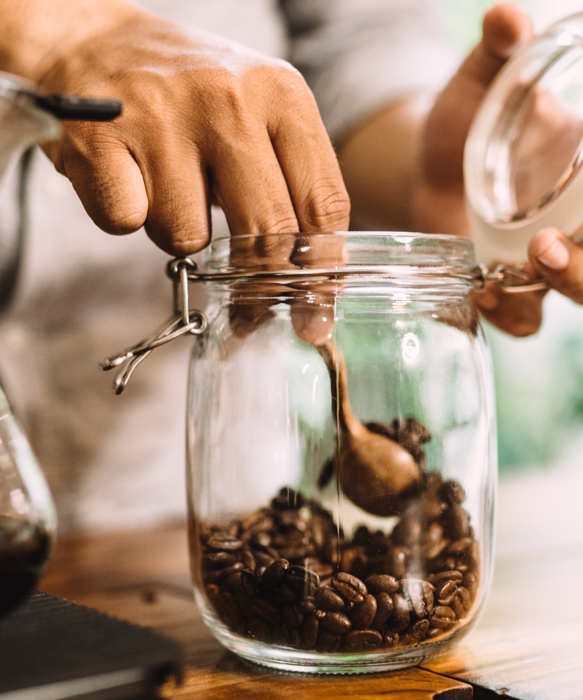 Eine Person nimmt geröstete Kaffeebohnen aus einem Einmachglas.