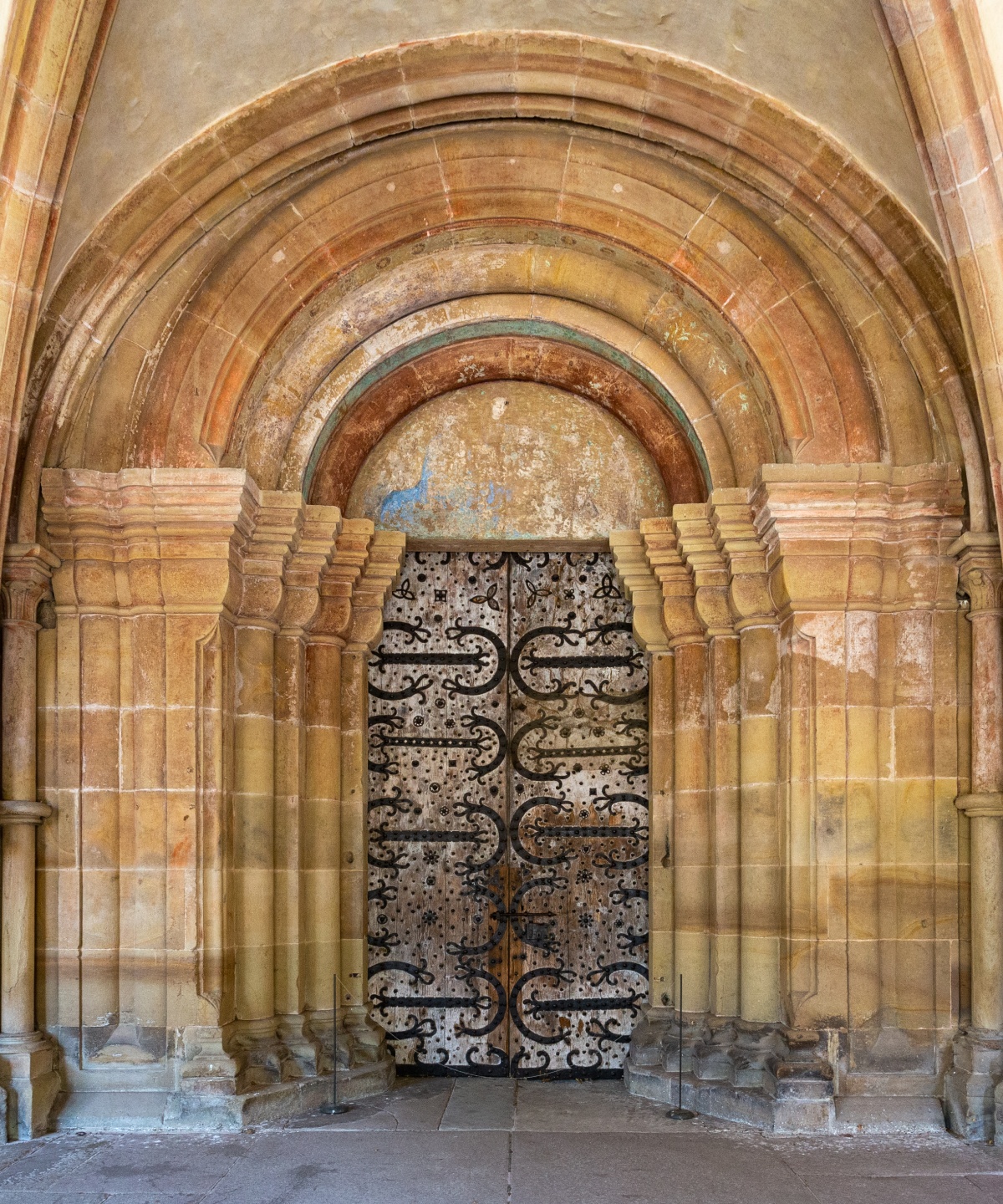 Gotisches Tor von Kloster Maulbronn mit verzierten Eisenbeschlägen und sandsteinfarbenen Bögen.