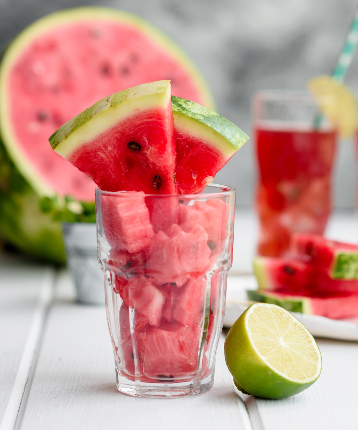 Ein Glas gefüllt mit kleinen Wassermelonen-Häppchen und zwei großen Wassermelonen Schnitze