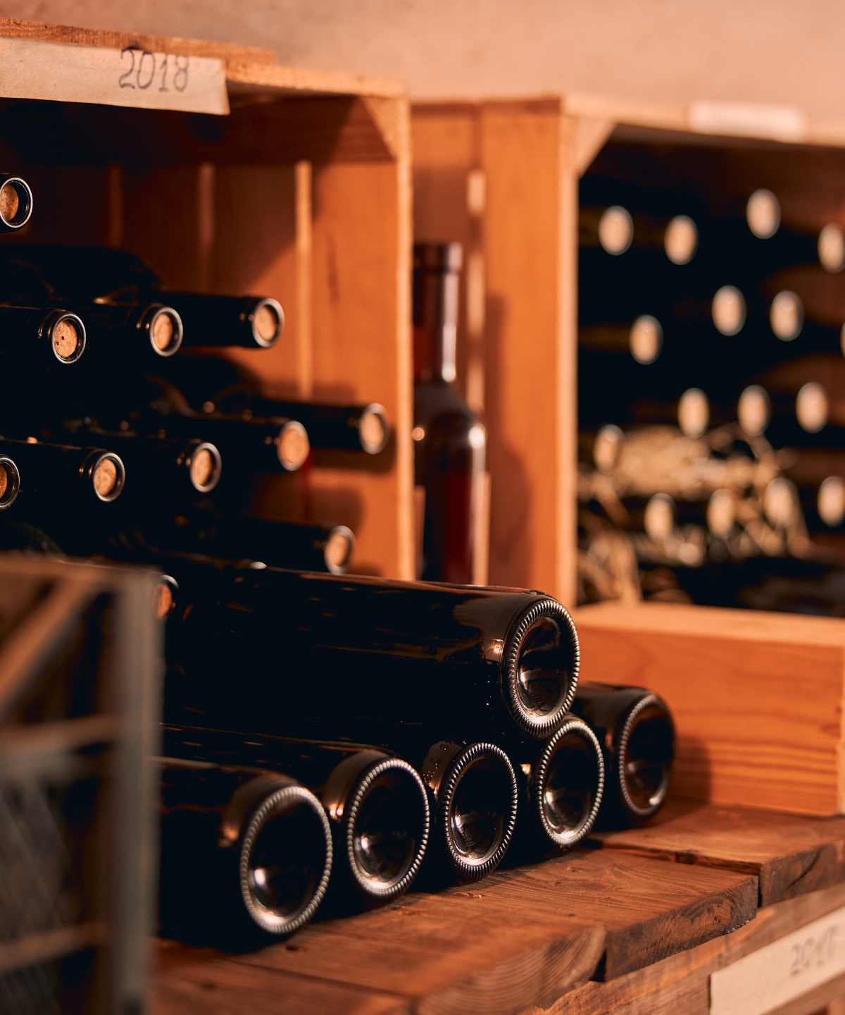 Weinflaschen mit Naturkorken lagern in Holzregalen.