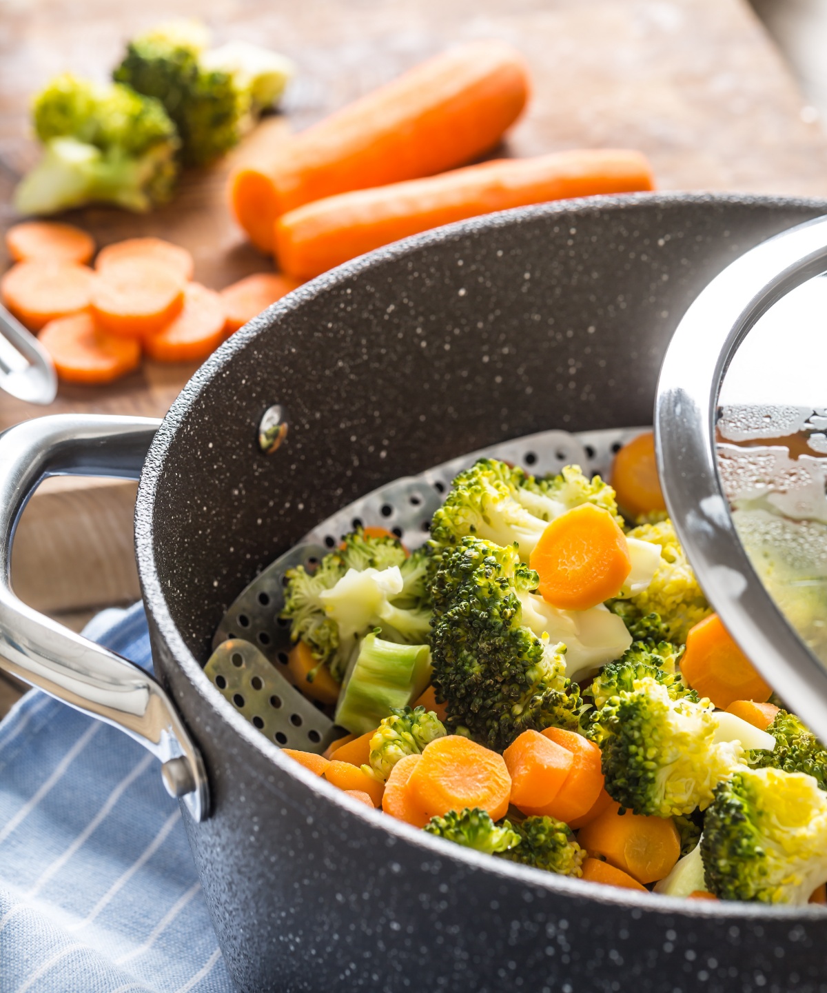 Ein Kochtopf mit Gareinsatz und Brokkoli, sowie Karotten.