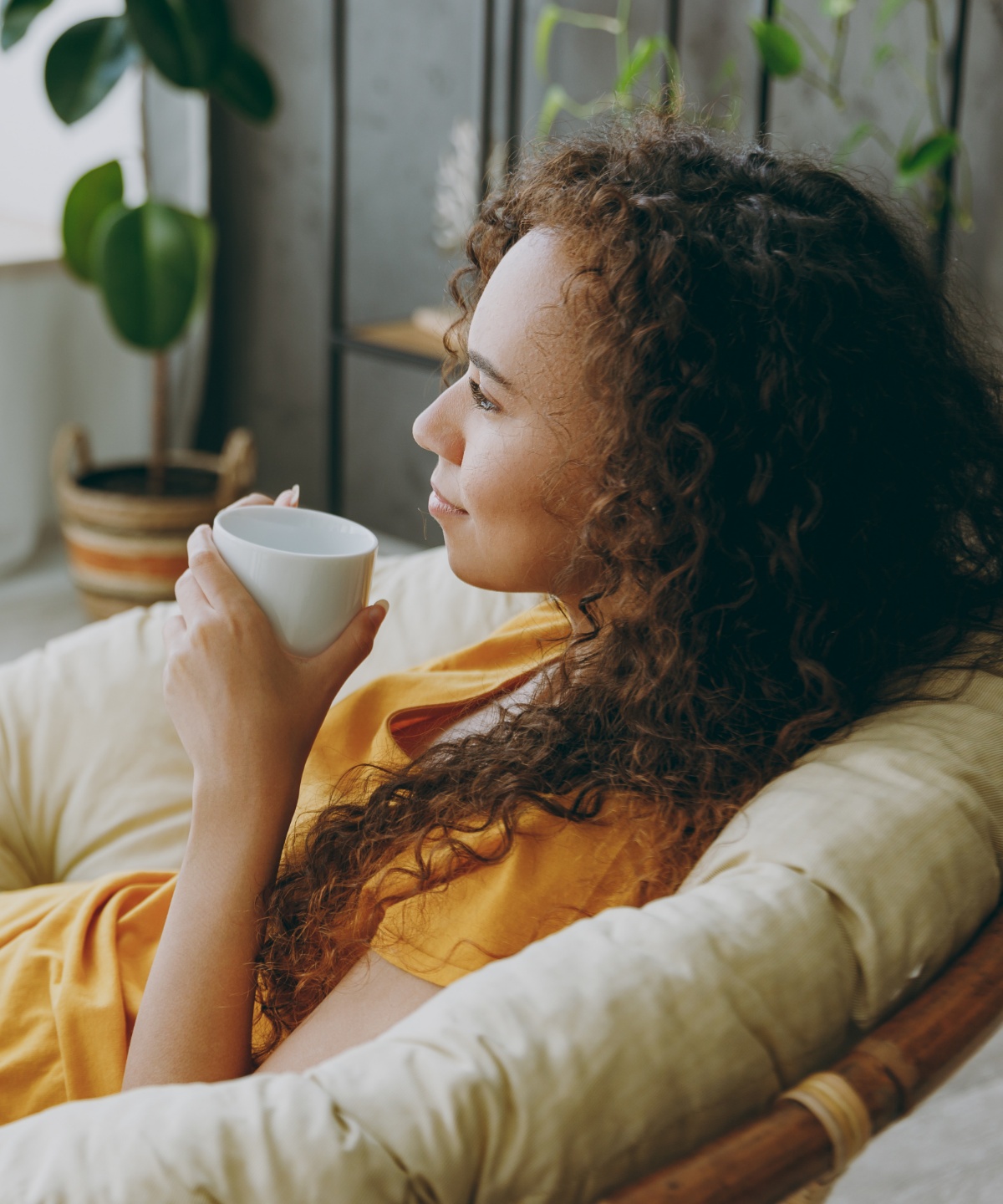 Eine Frau entspannt sich mit einer Tasse Tee in einem Sessel.