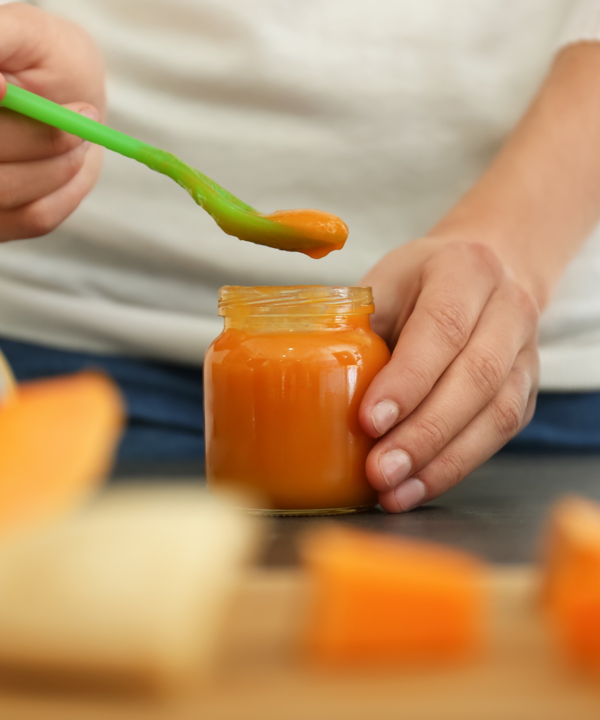 Eine Person löffelt  selbst gemachten Babybrei aus einem Gläschen.