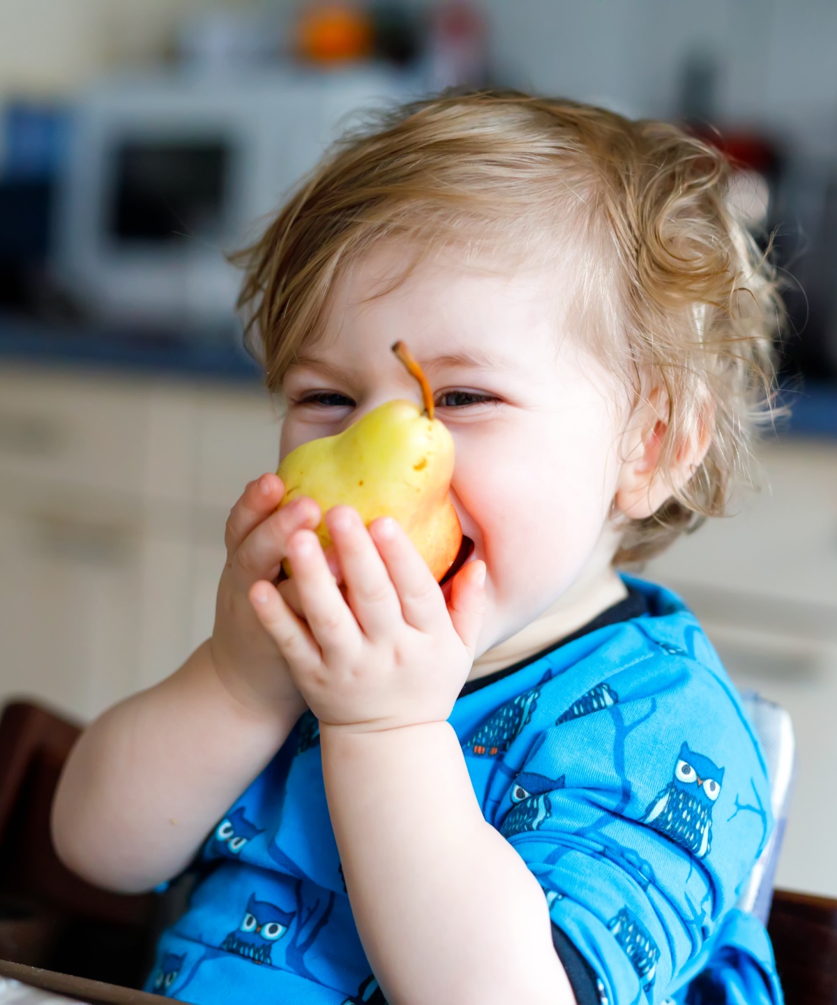 Ein Kleinkind beißt herzhaft in eine frische Birne.