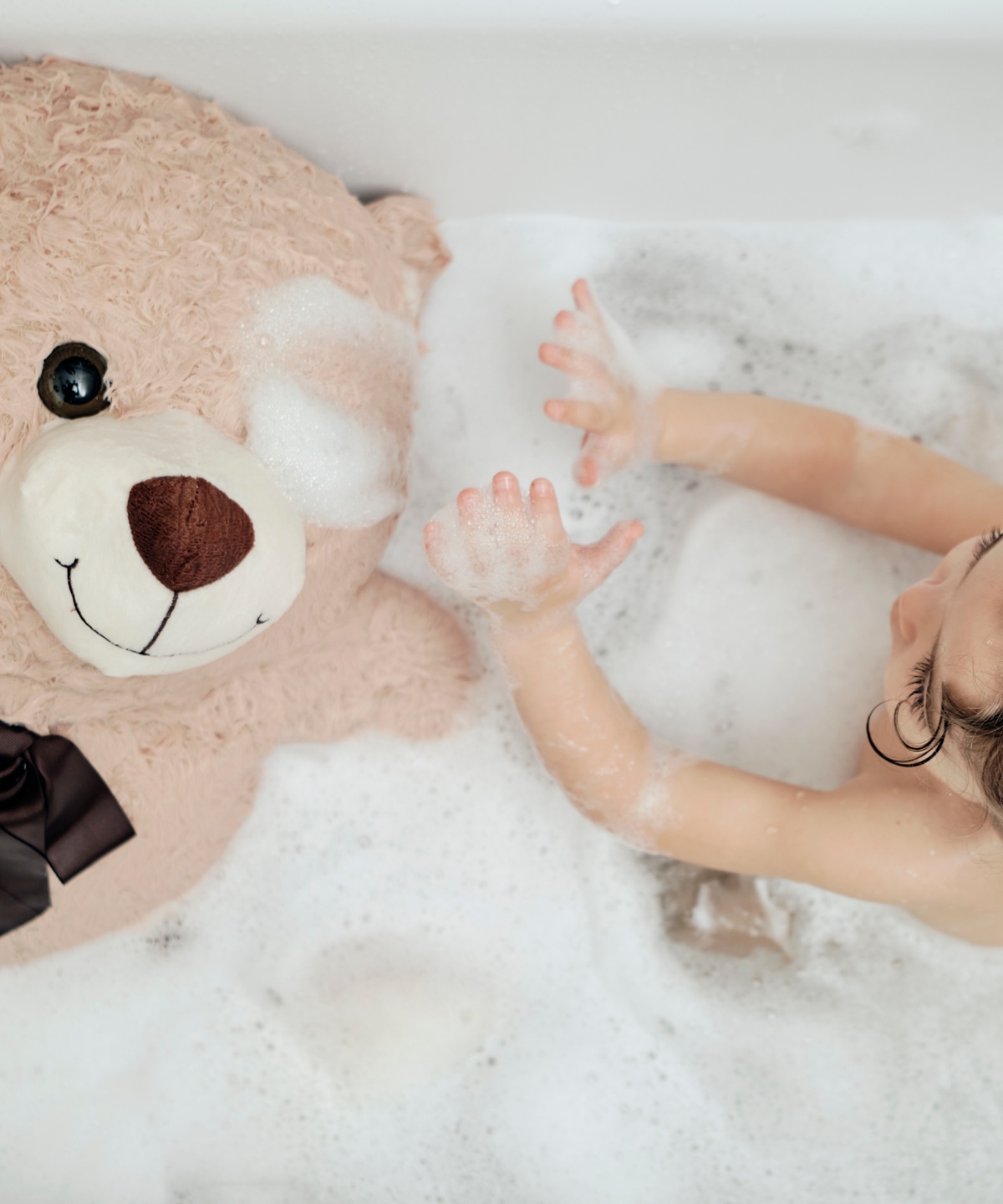 Ein Kind ist zusammen mit seinem lieblings Teddy in der Badewanne am baden.