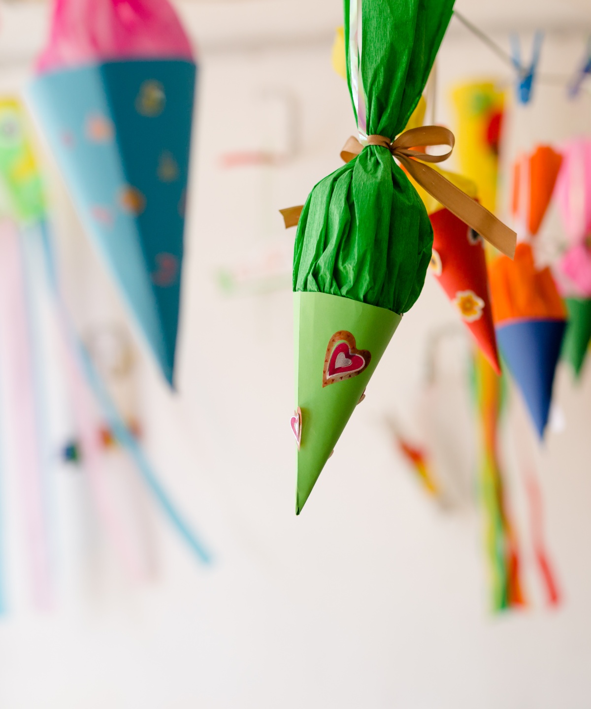 Bunte Schultüten mit Herzen und anderen Dekorationen hängen von der Wand.