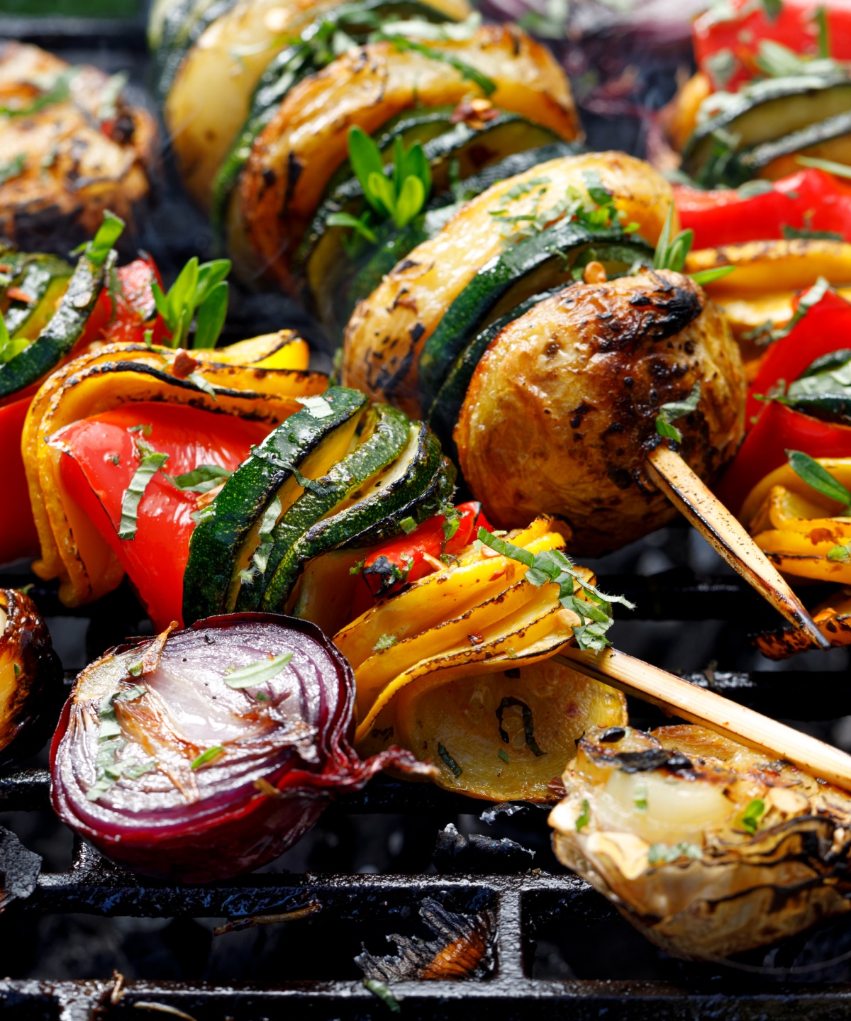 Vegetarische Gemüse-Spieße liegen auf einem Grillrost.