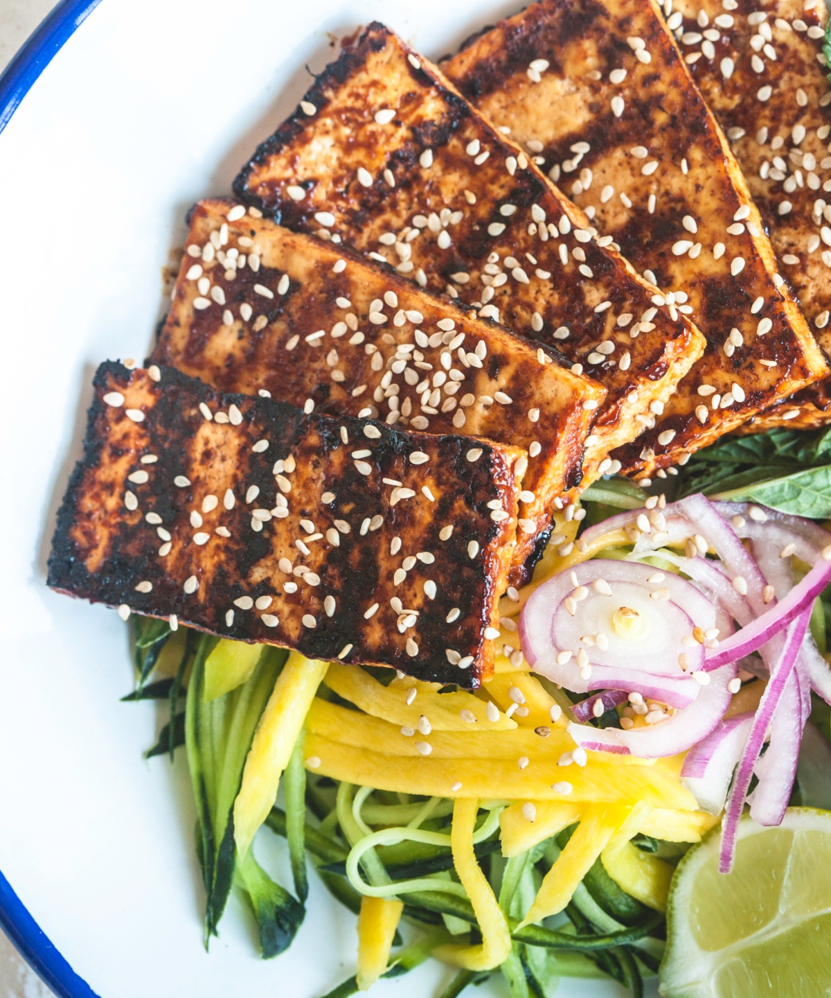 Goldbraun gegrillter Tofu liegt auf frischem Salat.