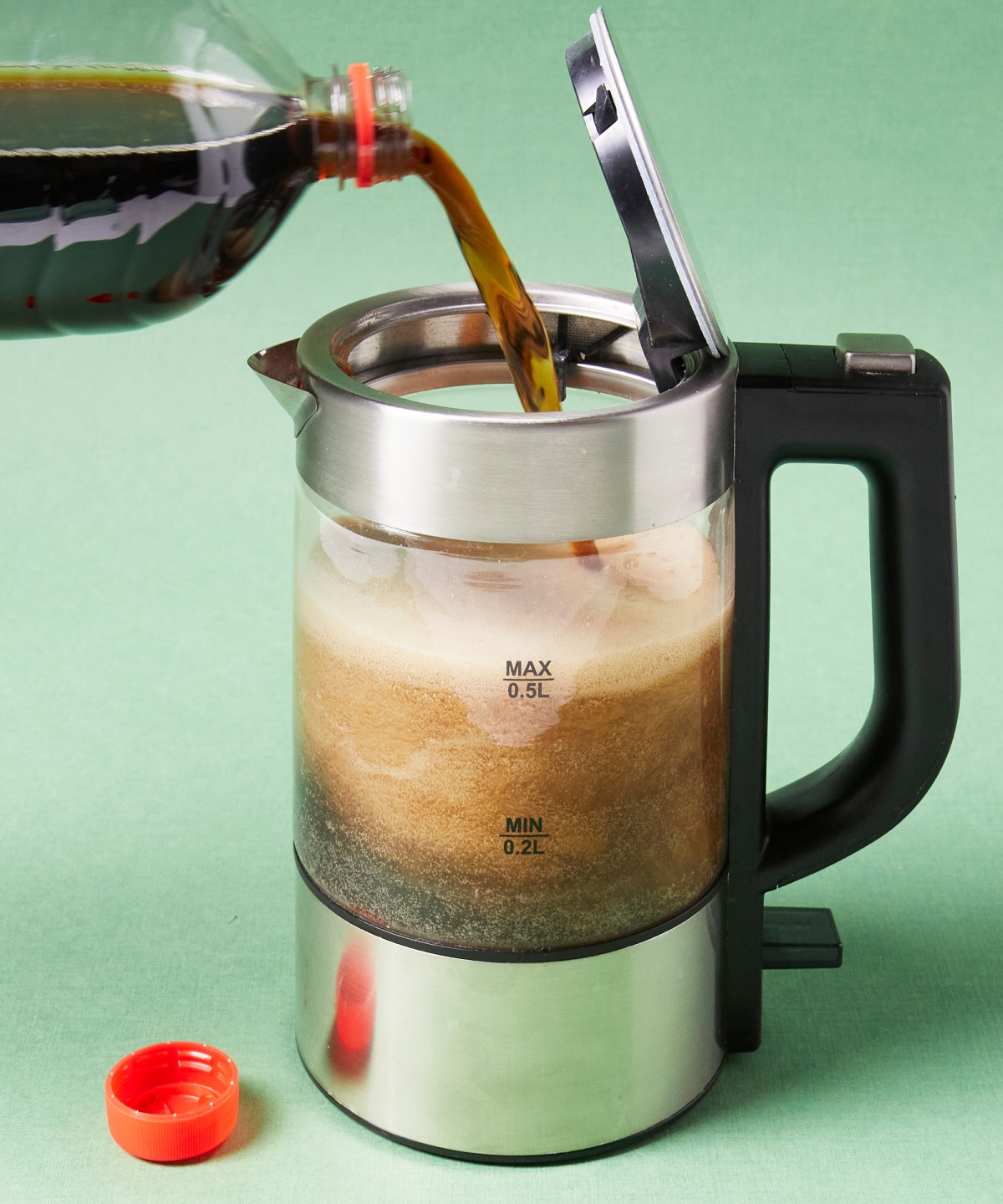 Ein Wasserkocher wird gerade mit Cola befüllt.
