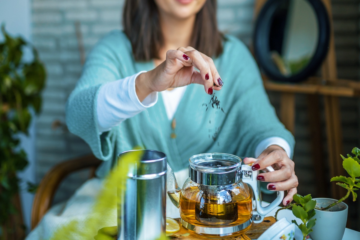 Getrocknete Kräuter werden in eine Teekanne gegeben