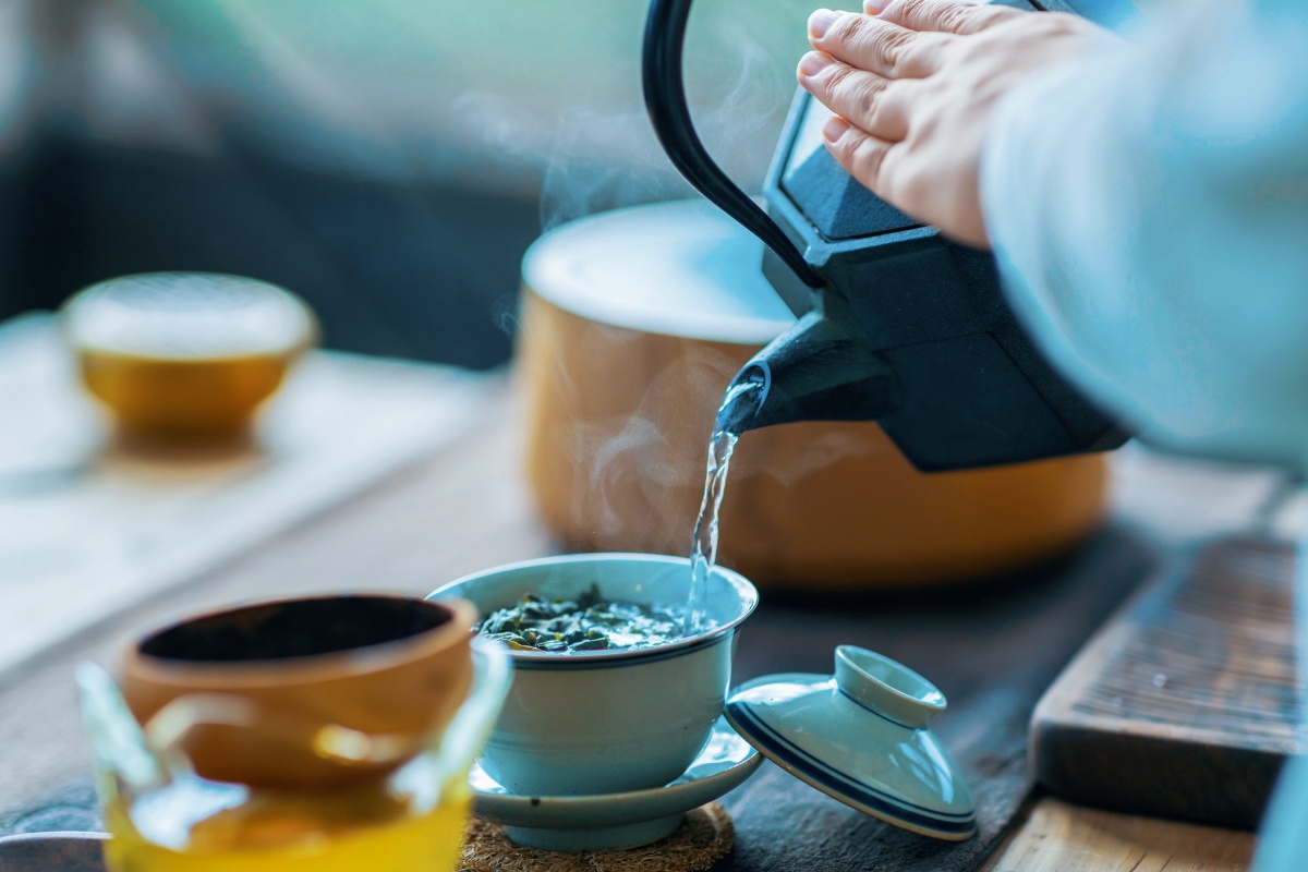 Eine Tasse voller Kräuter wird mit heißem Wasser aufgegossen