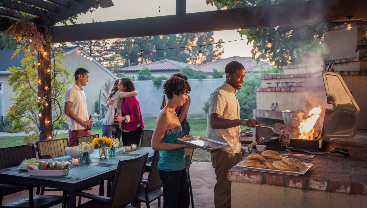 Eine Gruppe von Freunden bei einem Grillend mit Outdoorküche.