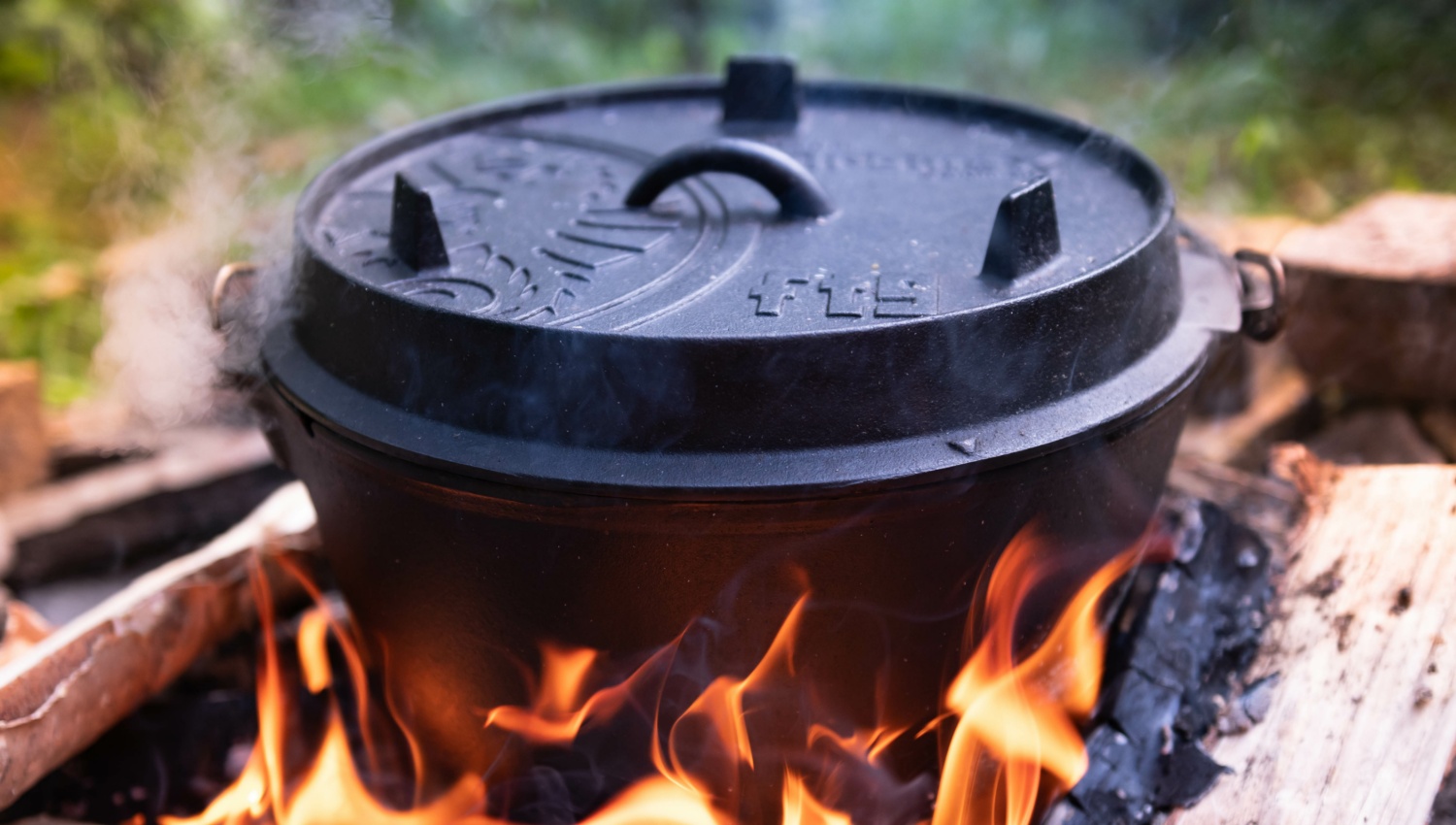 Dampfender Dutch Oven auf von Holzkohle gespeister offener Flamme.