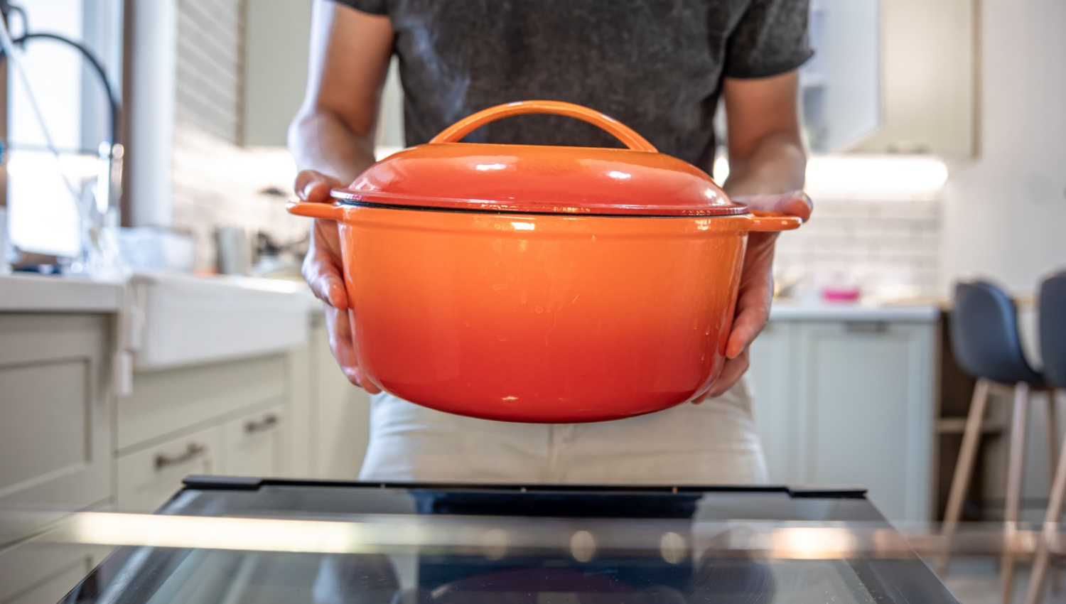 Eine Person hält einen roten Schmortopf.