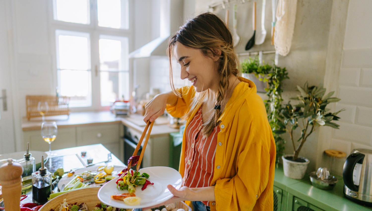 Eine junge Frau nimmt sich Salat auf den Teller.