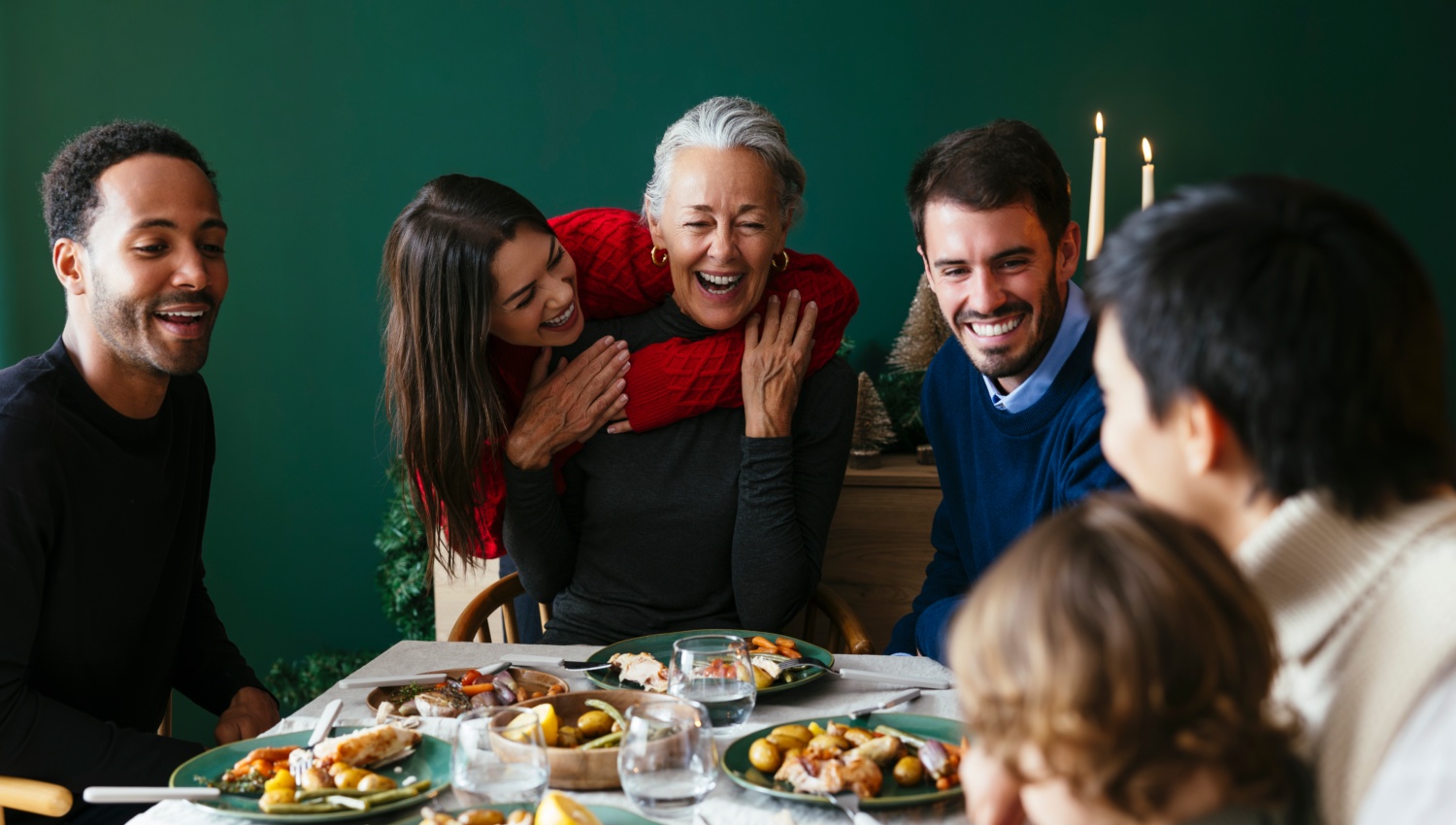 Eine Familie sitzt an einem festlich gedeckten Tisch zu Weihnachten.