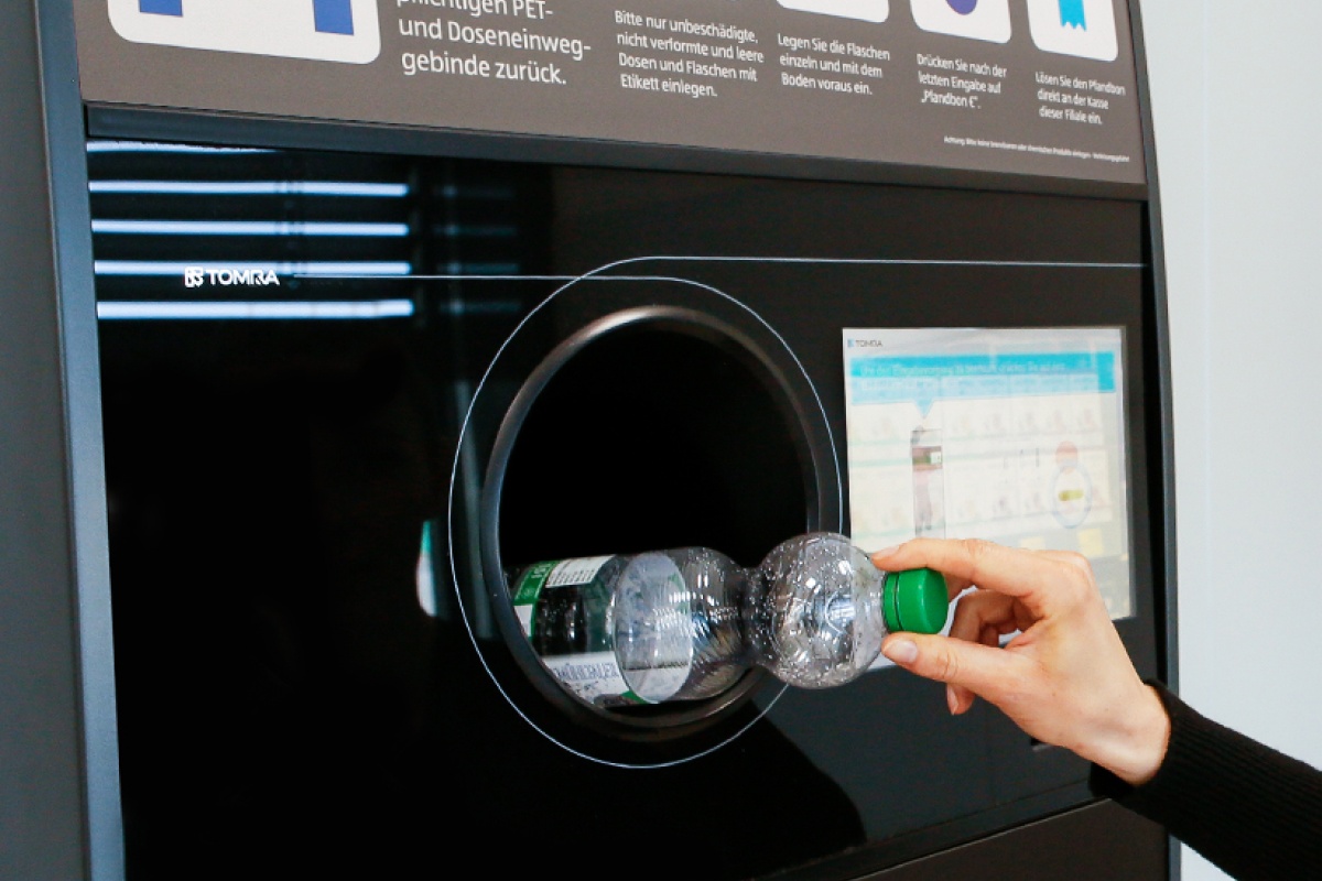 Eine Person recyclet gerade eine PET Flasche an einem ALDI SÜD Getränkeautomaten.