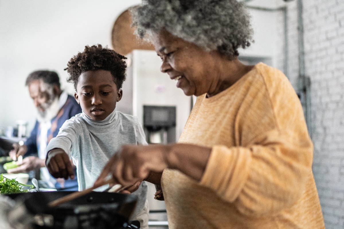 Kind, Großmutter und Großvater kochen gemeinsam in der Küche.
