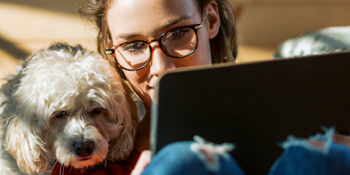 Frau und Hund gucken auf ein Tablet.