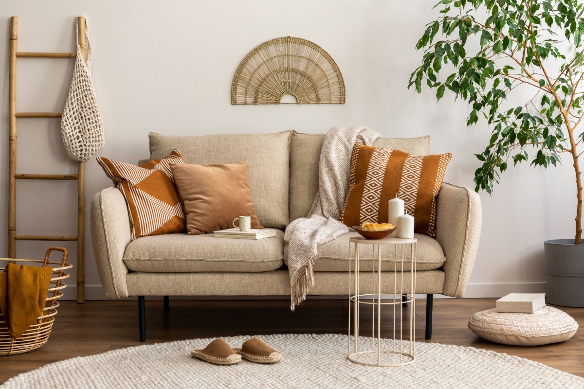 Ein helles Sofa im trendigen Boho-Stil mit Kissen, Decken und Accessoires