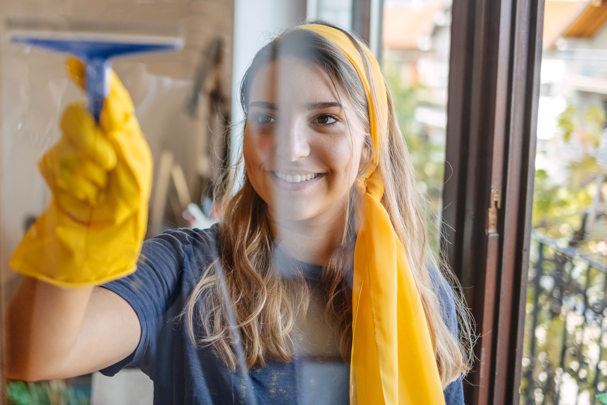 Eine Frau putzt ihre Scheiben mit einem Abzieher.