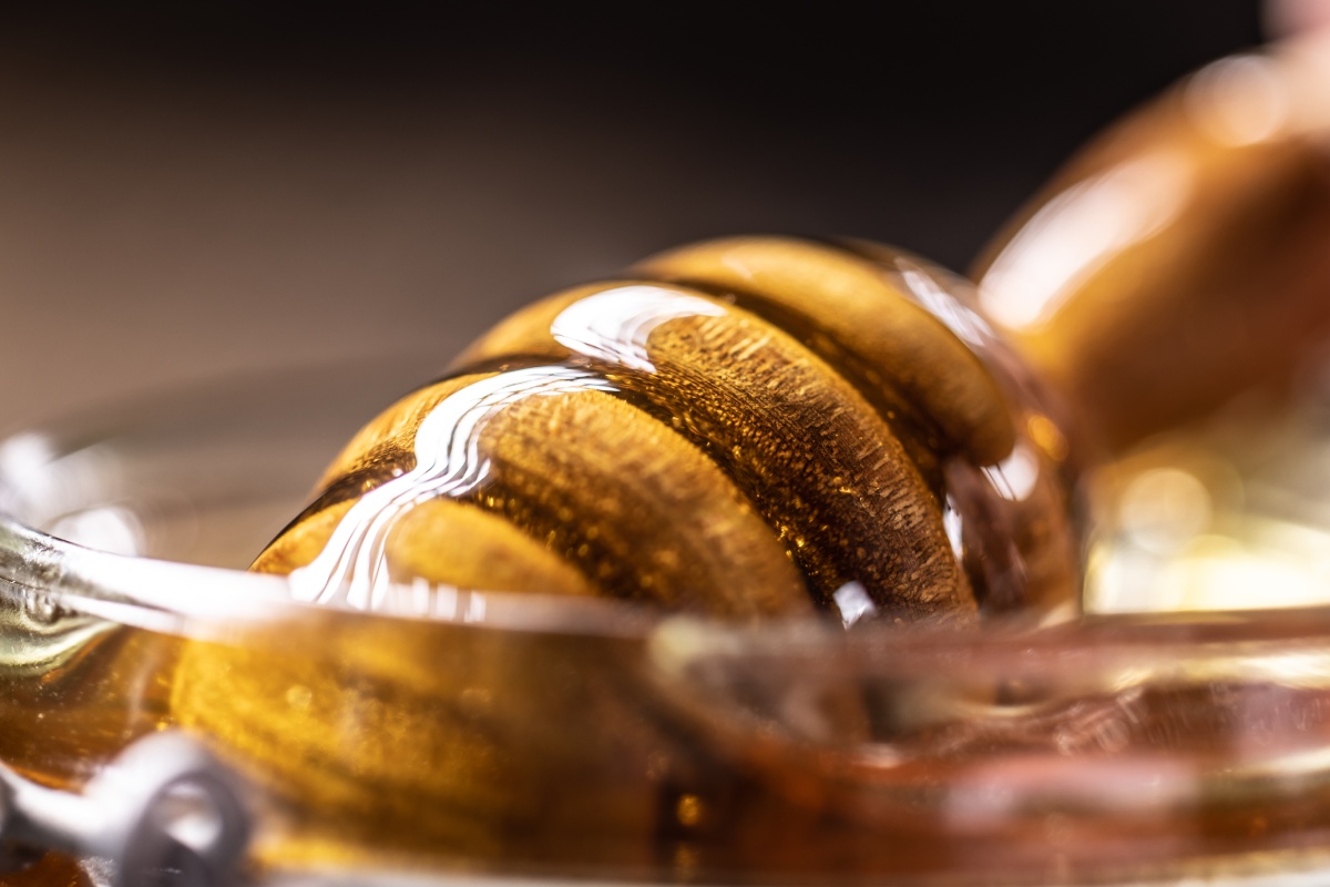 Nahaufnahme eines Honiglöffels mit frischem, goldfarbenem Honig.