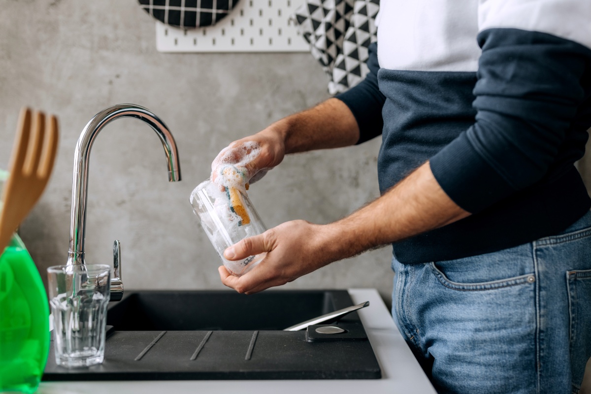 Mann spült ein Glas von Hand, um es für das Einkochen im Backofen vorzubereiten.