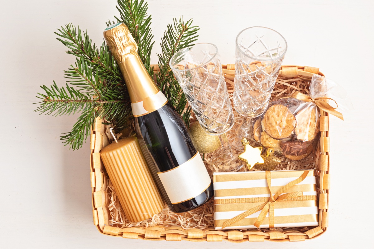 Geschenkkorb im Gold-Look mit Sekt, Gläsern- Leckereien und Dekoration.