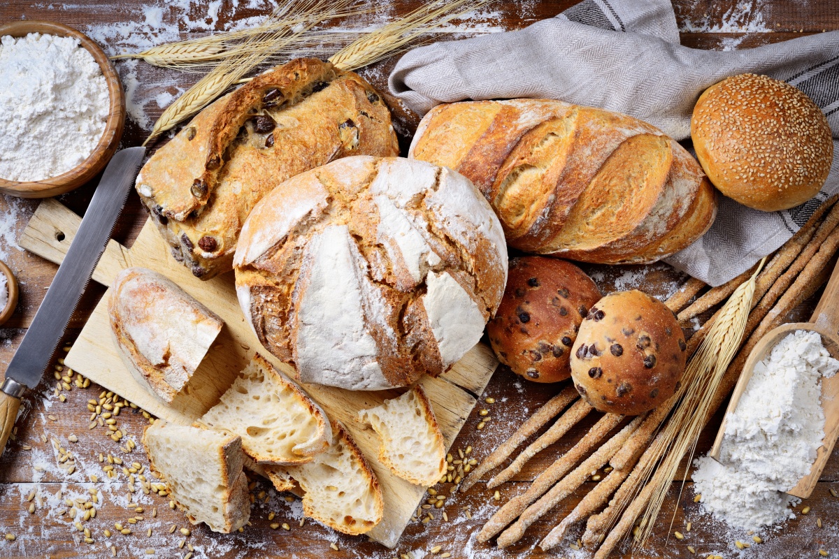 Knusprig gebackene glutenfreie Brote und Brötchen auf einem Holzbrett.