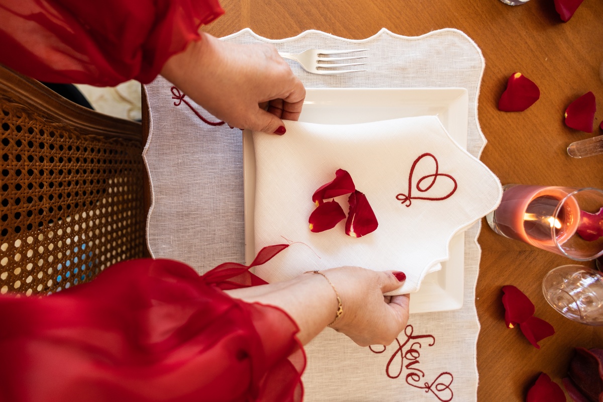 Festlich gedeckter Tisch in Weiß mit Rosenblättern.