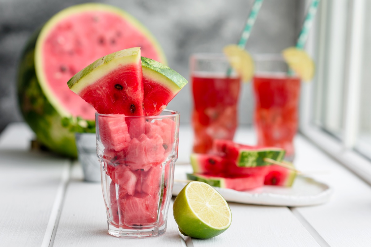 Ein Glas gefüllt mit kleinen Wassermelonen-Häppchen und zwei großen Wassermelonen Schnitze
