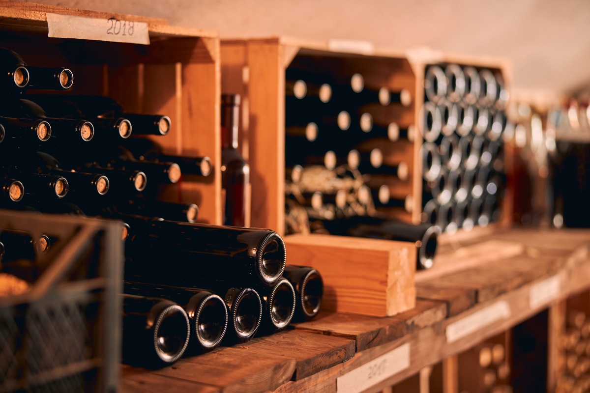 Weinflaschen mit Naturkorken lagern in Holzregalen.