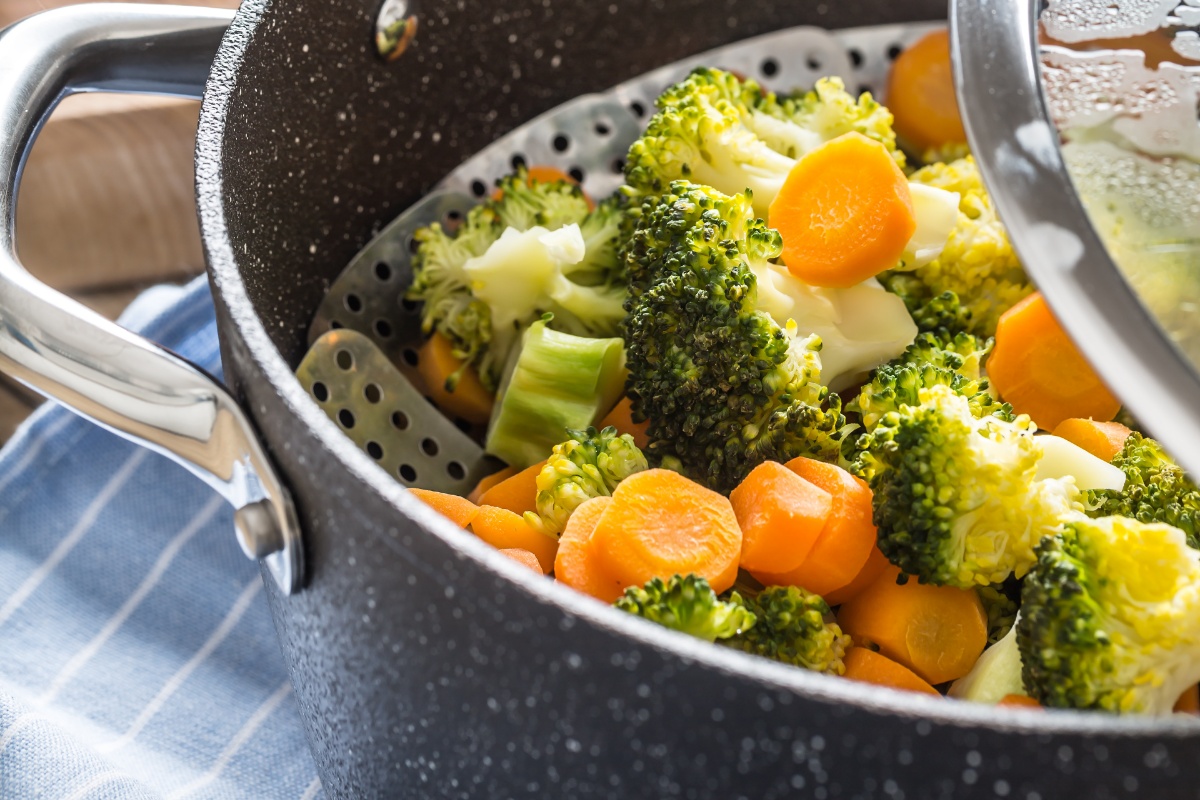 Ein Kochtopf mit Gareinsatz und Brokkoli, sowie Karotten.