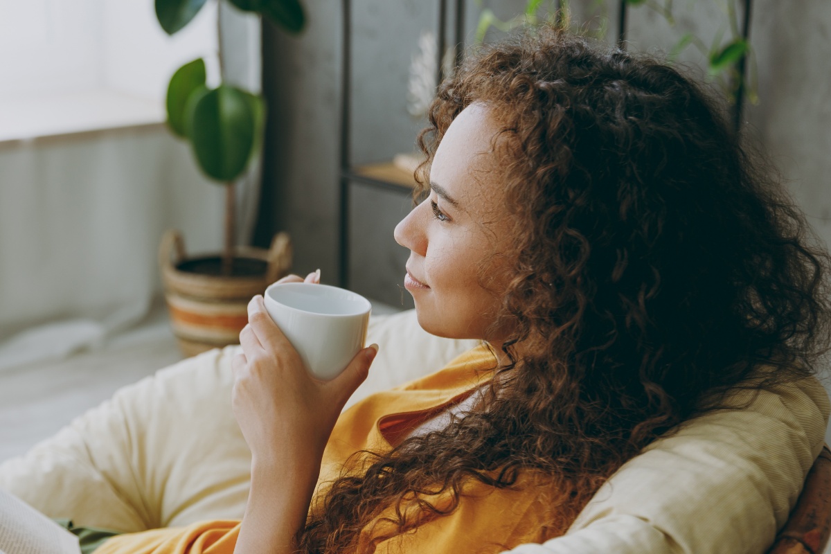 Eine Frau entspannt sich mit einer Tasse Tee in einem Sessel.