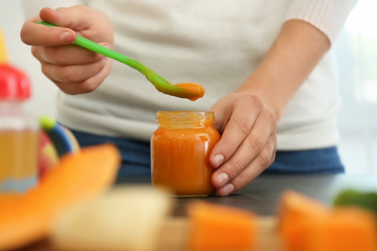 Eine Person löffelt  selbst gemachten Babybrei aus einem Gläschen.