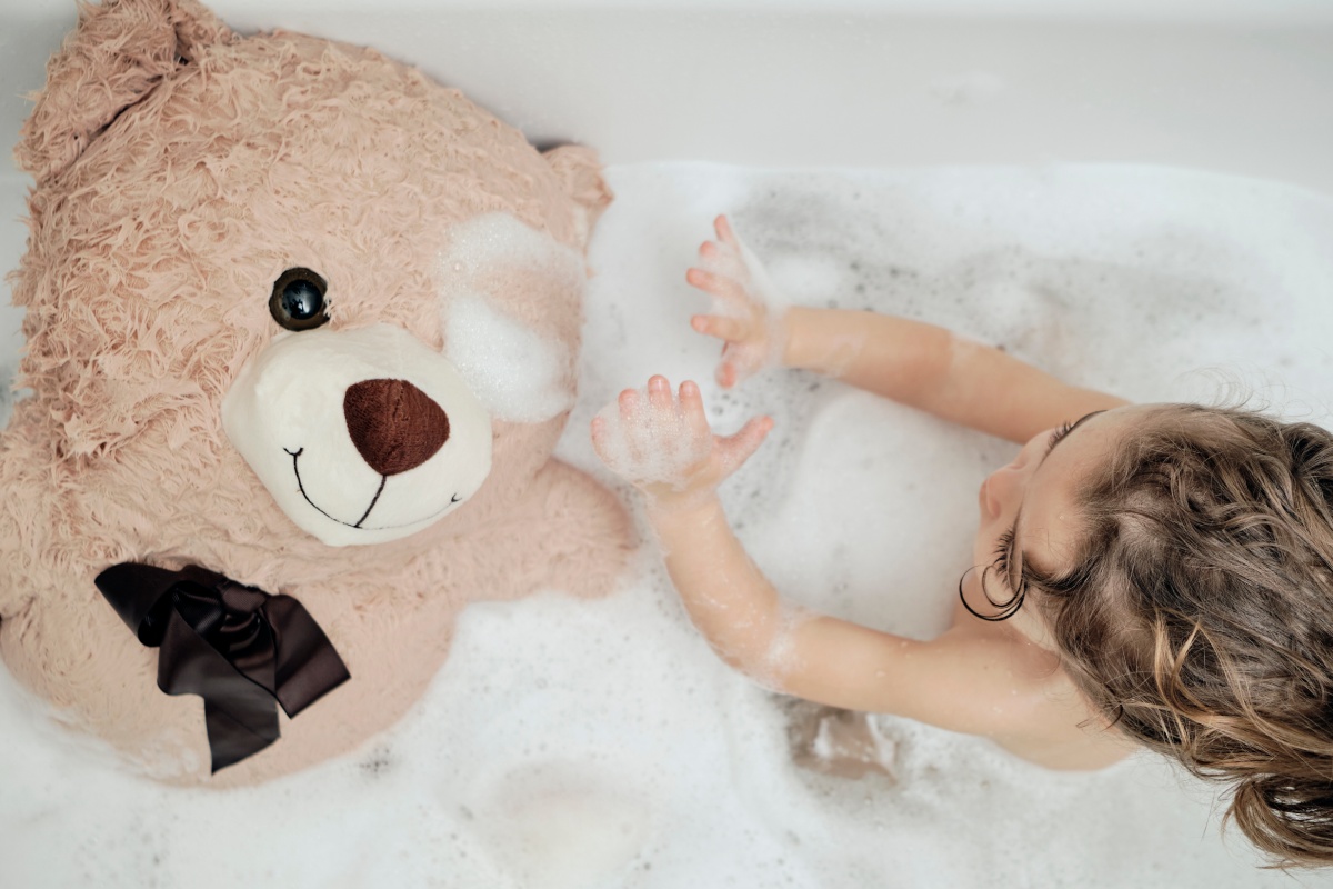 Ein Kind ist zusammen mit seinem lieblings Teddy in der Badewanne am baden.