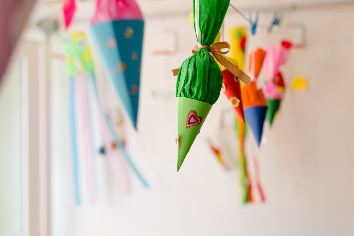 Bunte Schultüten mit Herzen und anderen Dekorationen hängen von der Wand.