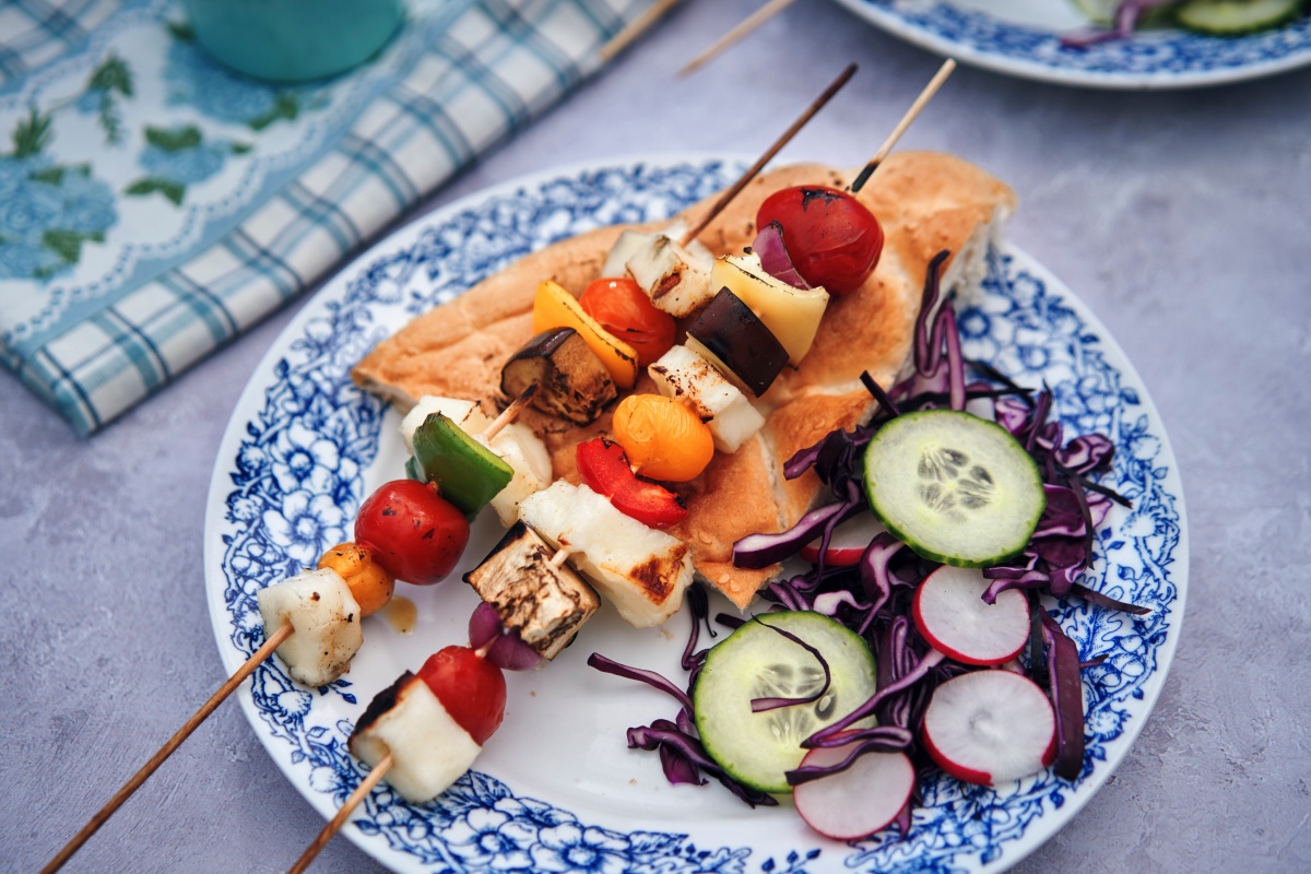 Ein Teller mit vegetarische Grillspießen, Rotkohl-Salat und einem Stück Fladenbrot.