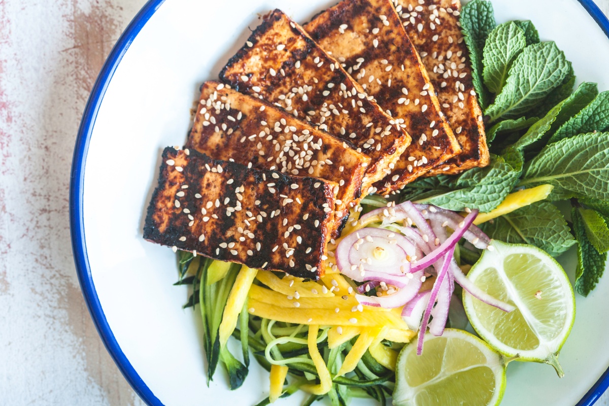 Goldbraun gegrillter Tofu liegt auf frischem Salat.