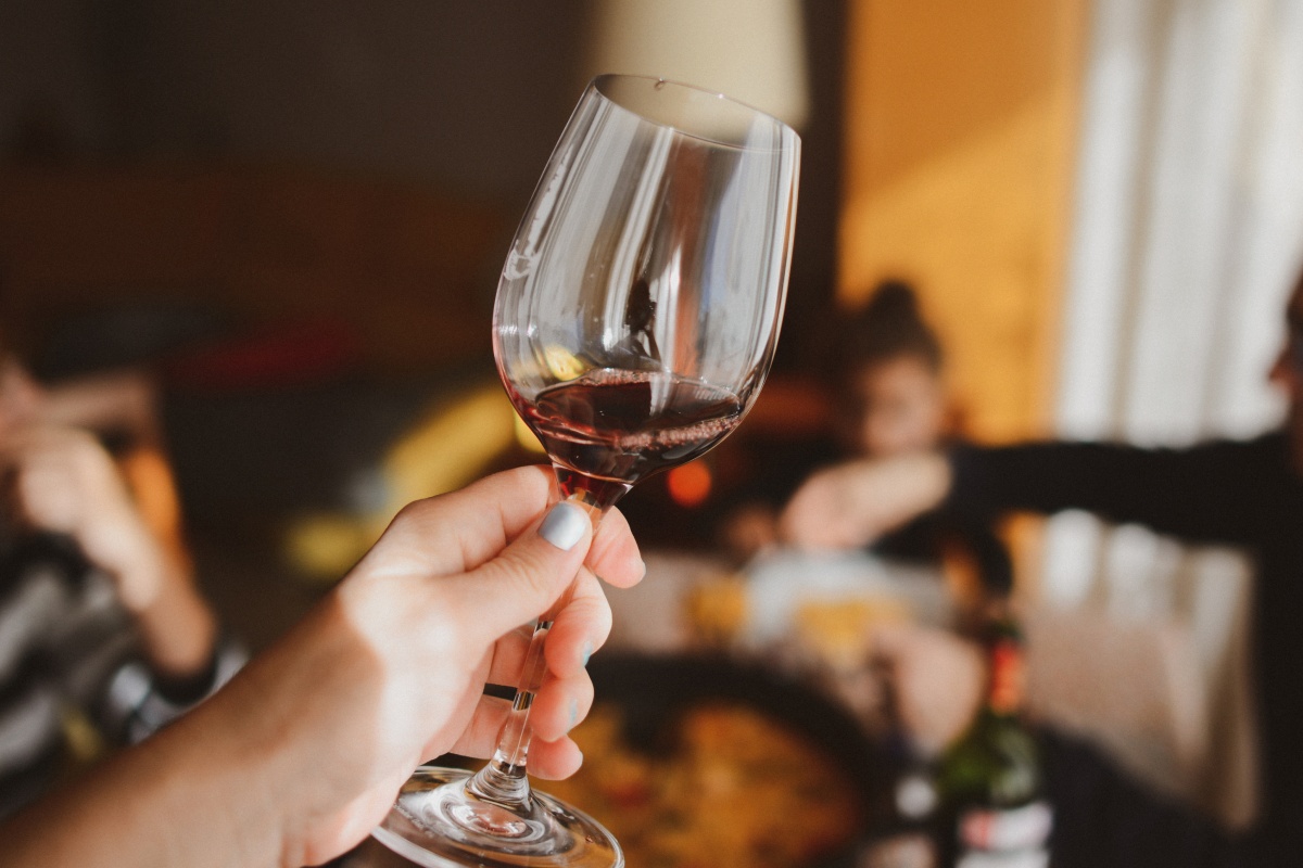 Person hält ein Weinglas mit Rotwein in der Hand.