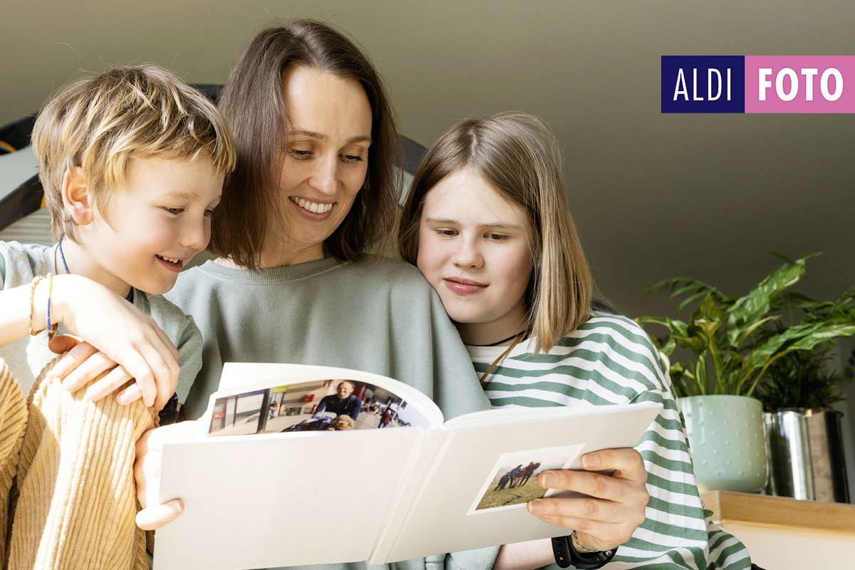 Mutter und Kinder blättern gemeinsam in einem Fotobuch.